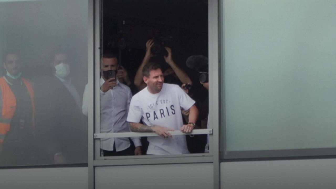 Lionel Messi waves to fans from Paris airport window