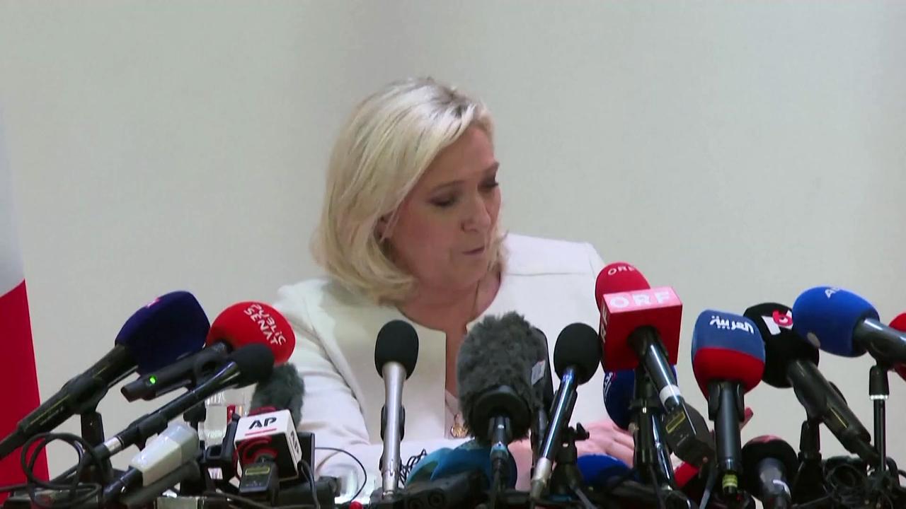 Woman bearing sign showing Putin and Le Pen dragged out of press conference