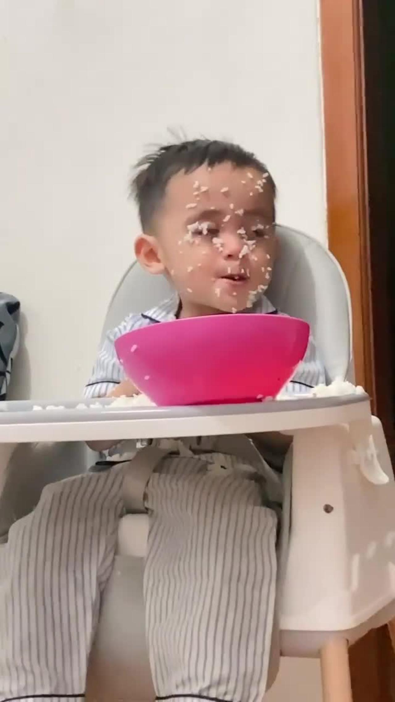 cute baby eats rice until it dirty his face