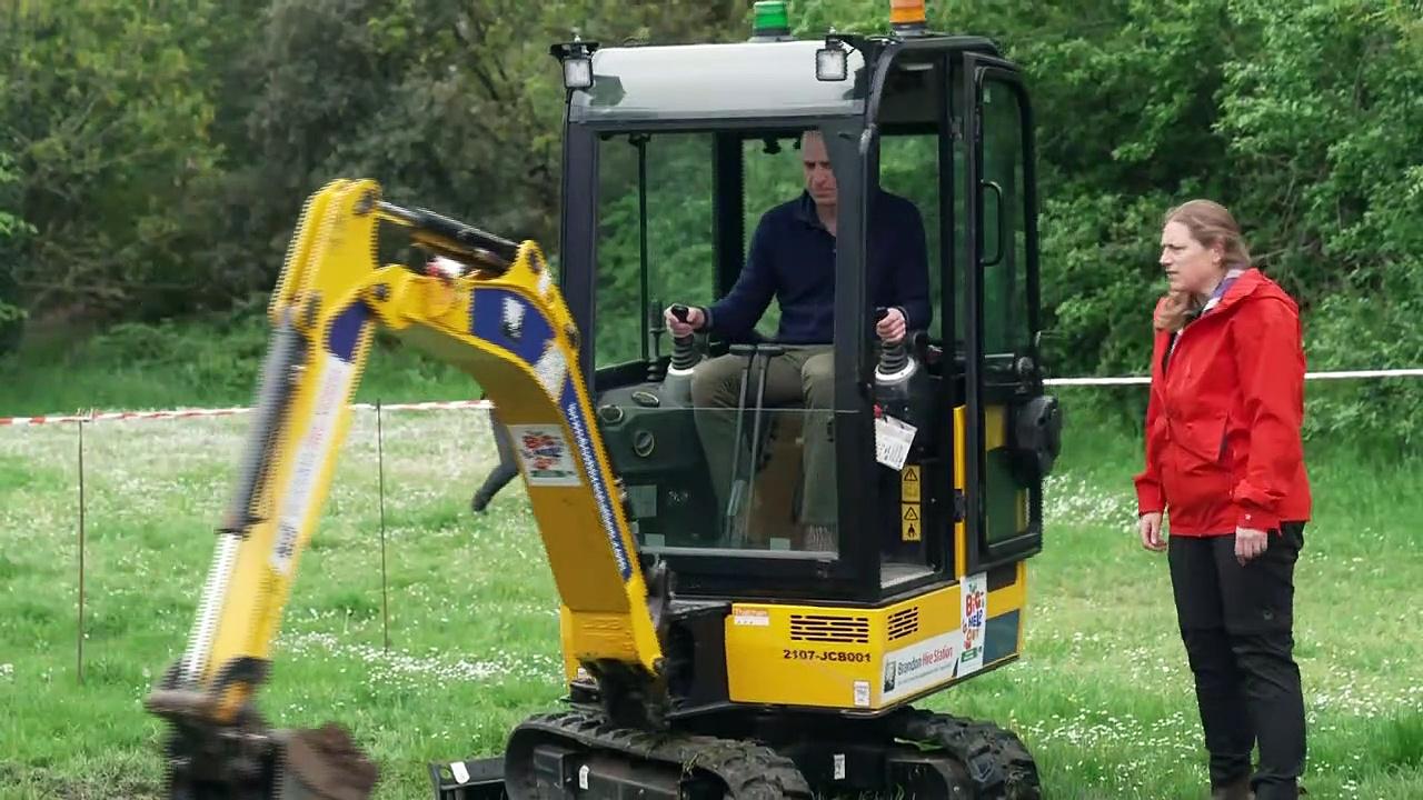 Prince George and Prince Louis drive a digger at scout hut
