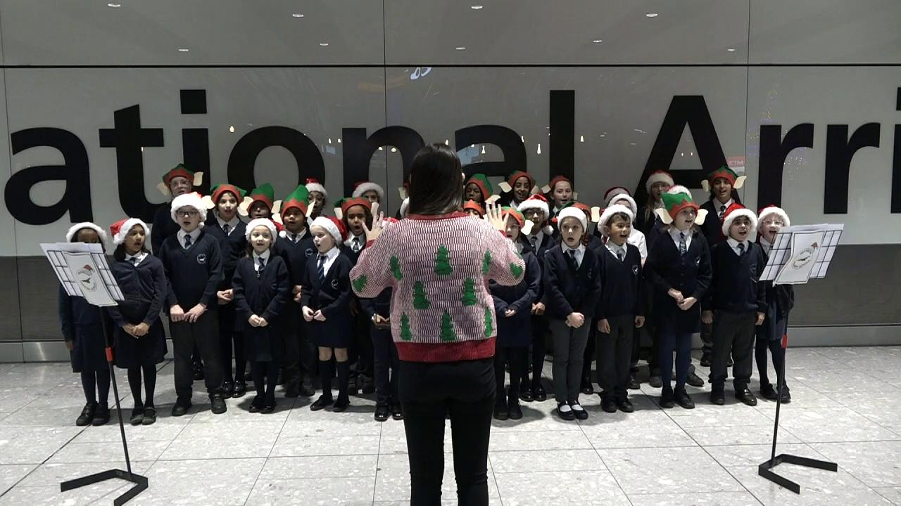 Pupils welcome travellers with carols at Heathrow