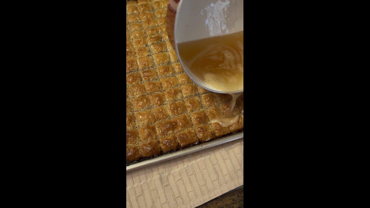 Pouring honey, lemon, butter and sugar over baklava