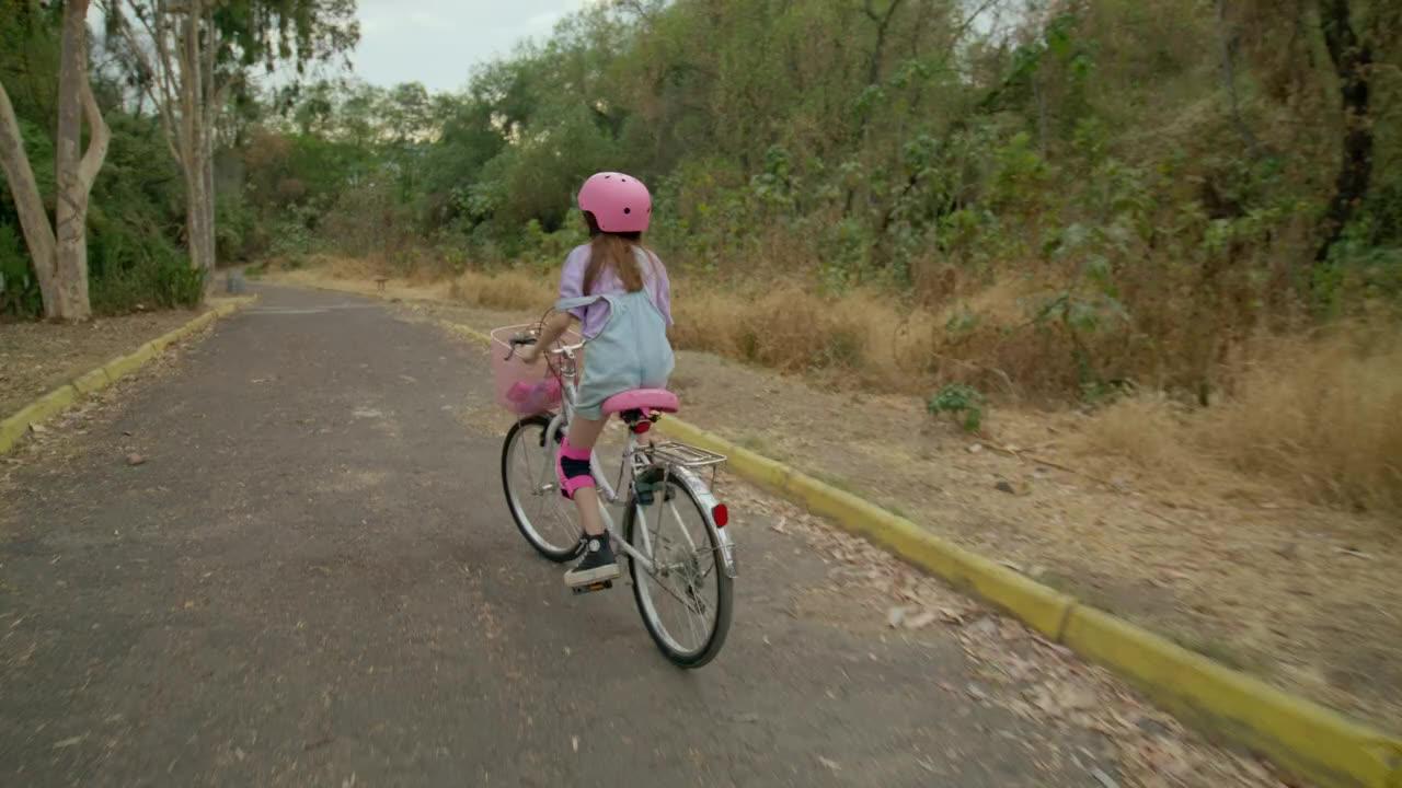 A little girl cruises through the forest path on her bike