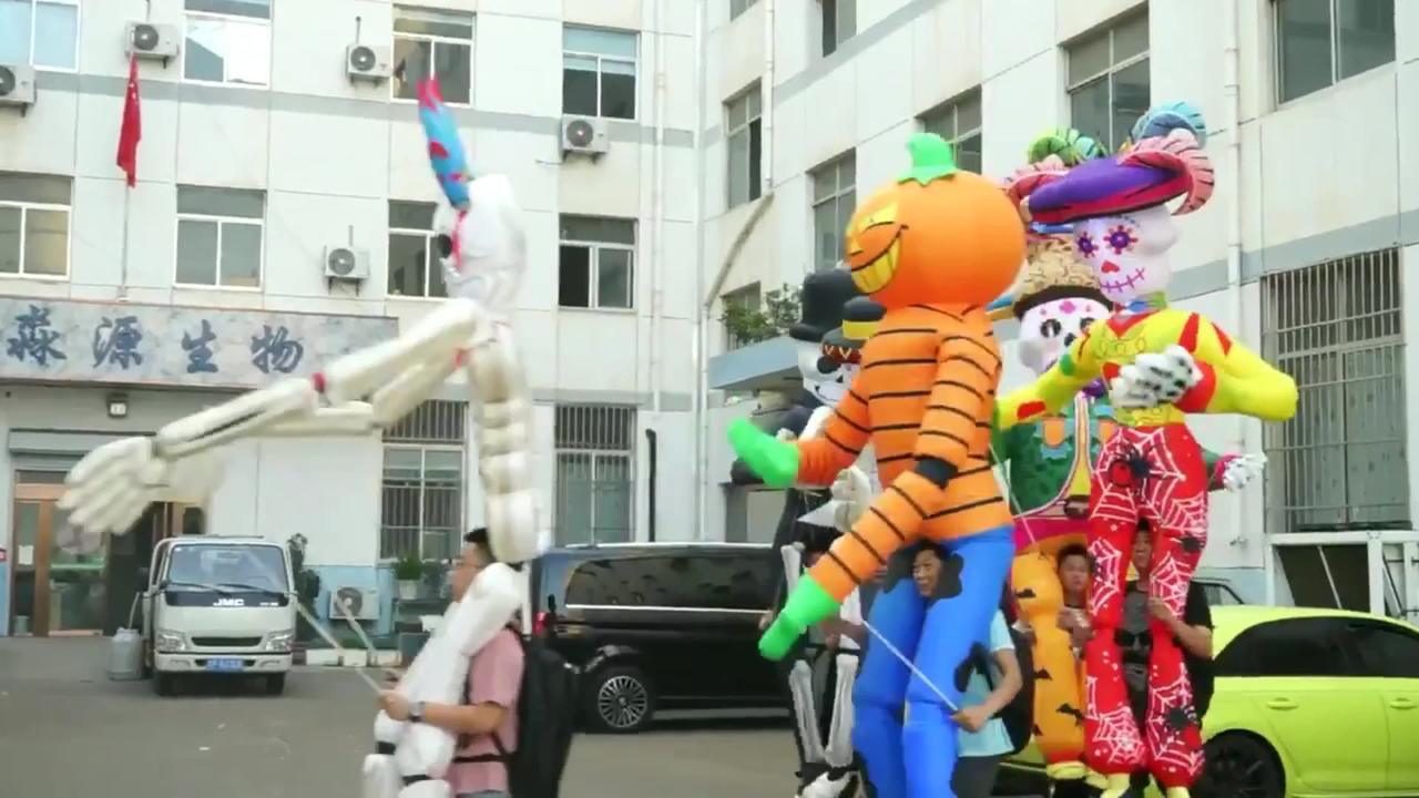 People Walk Around With Inflatable Halloween Puppets Overhead.