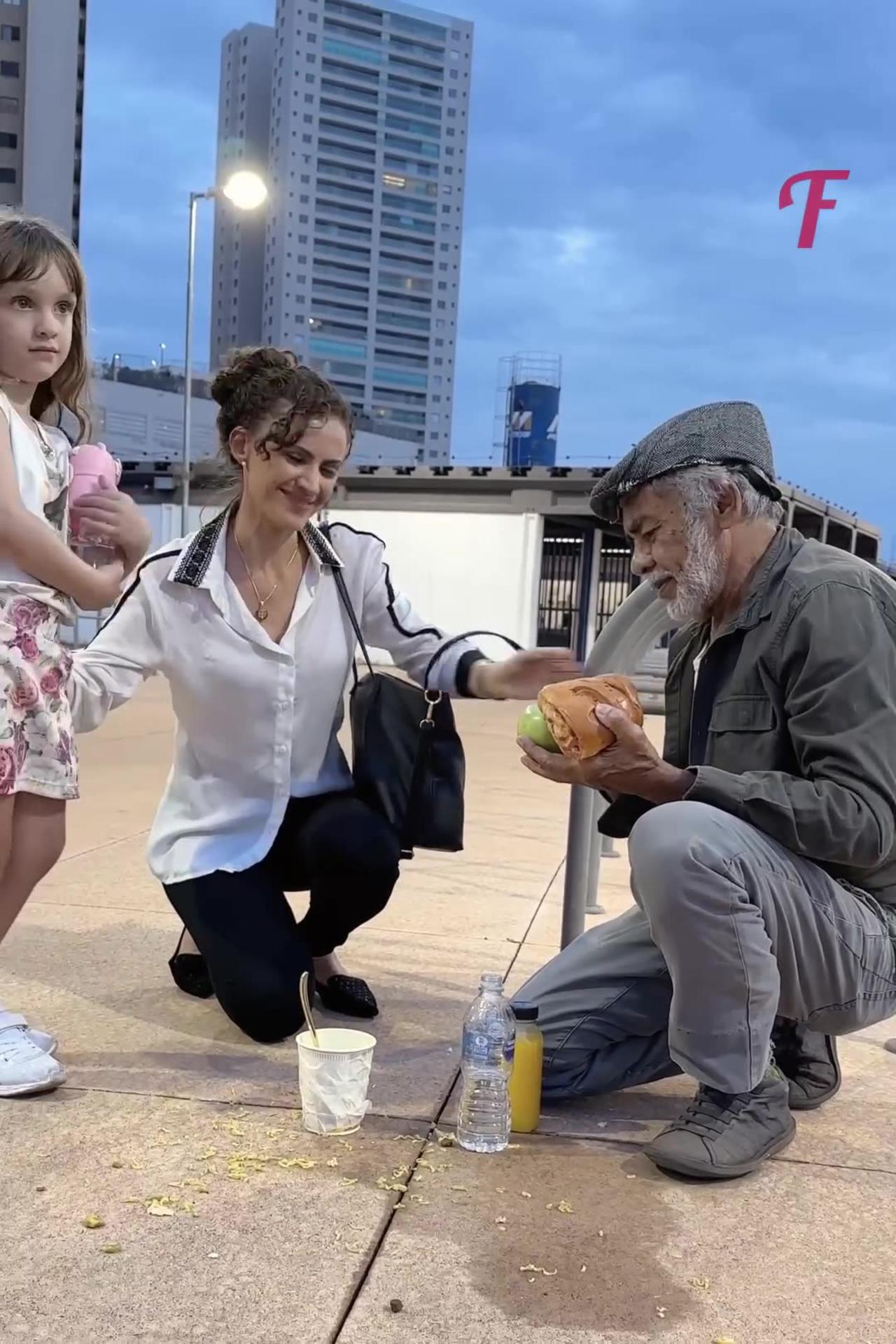 A mother and daughter extend a helping hand to a homeless man