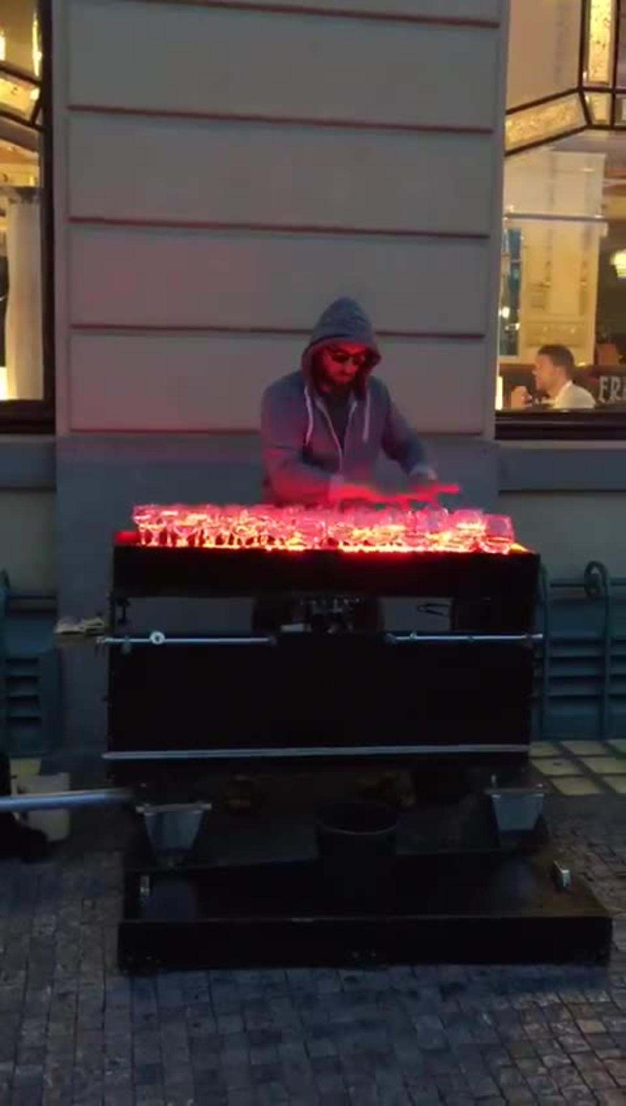 A street musician in Prague is playing music through a glass of water