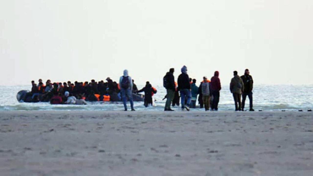 Migrants board dinghy in French shallow sea water